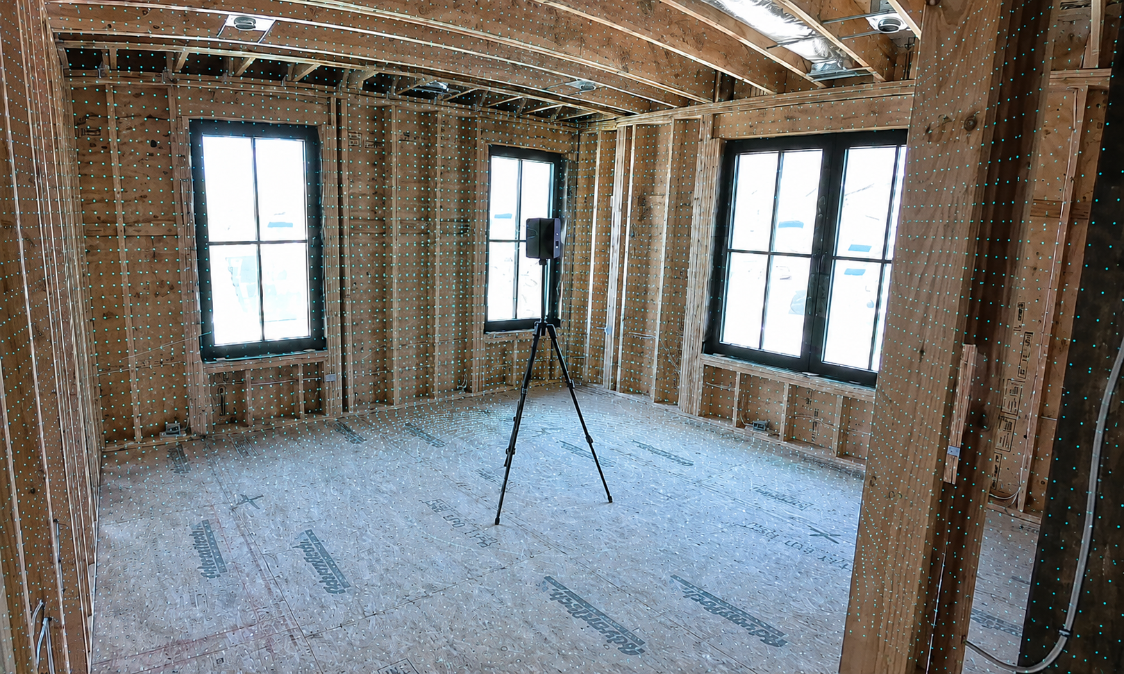 LiDAR scanner capturing point-cloud data inside a framed construction interior